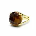 Nahaufnahme eines Rings mit facettiertem Tigerauge-Stein und Goldband auf Weiß. - Tigerauge
