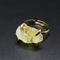 Close-up detail of a natural raw crystal ring with an adjustable gold-plated claw setting - Citrine