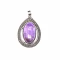 Close-up of a vintage purple amethyst crystal teardrop pendant in an ornate silver setting. - Amethyst