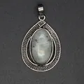 Close-up of a vintage silver teardrop pendant featuring an oval white crystal stone. - Labradorite