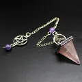 Gros plan d'un pendule en quartz rose avec une chaîne argentée et un charme pentacle - Quartz rose
