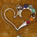 Close-up of heart-shaped silver pendant with seven colorful chakra gemstones on straw - Heart Style (7)