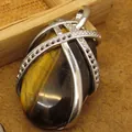 Polished natural tiger eye gemstone pendant with an elegant silver-tone lattice design wrap - Tiger's Eye Pendant