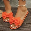 Sandali piatti arancioni vivaci con un grande fiocco decorativo per un look estivo chic - Arancione