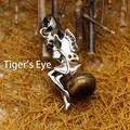 Silver fairy pendant sitting on a polished tiger eye stone sphere - Tiger's Eye