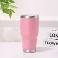 Detalle de un vaso térmico rosa de 30 oz de acero inoxidable con tapa en la mesa. - Rosa
