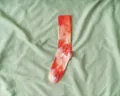 Vibrant orange and pink tie-dye crew socks displayed on a light green fabric background - One Size / Orange Red