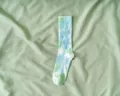 Eleganti calze tie-dye blu e verdi a metà polpaccio su sfondo di morbido tessuto verde - Taglia unica / Verde chiaro