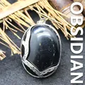 Polierter ovaler schwarzer Obsidian-Anhänger mit silbernem Metallrahmen auf Bambushintergrund - Obsidian