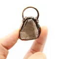 Macro view of a rustic copper-framed raw smoky quartz crystal pendant held in human hand - Smoky Quartz