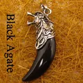 Black onyx wolf tooth pendant with detailed silver wolf head motif on straw background - Wolf Tooth / Black Agate