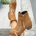 Detailed view of brown suede Chelsea boots featuring white embroidery and a block heel. - 36 / Coffee