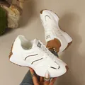 Close-up of white women's chunky sneakers with brown rubber soles and gold accents. - 36 / White