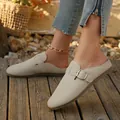 Beige suede round toe flat backless loafers with metal buckle detail on wooden floor - Beige With Belt Buckle