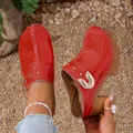 Close-up of glossy red patent leather clogs featuring metallic rivets and chunky heels. - 35 / Red