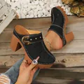 Close-up of black closed-toe platform clogs with flower cutouts and high thick heels - 36 / Black
