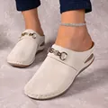 Detailed view of women's beige wedge clogs featuring a decorative gold chain buckle - 36 / White