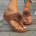 Macro detail of brown wedge thong sandals with large 3D flower and white stitching - Khaki