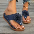 Detailed view of navy blue wedge flip-flop sandals featuring a large decorative 3D flower - Dark Blue