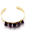 Gold cuff bracelet featuring five raw irregular purple amethyst stones on white background - Amethyst Bangle