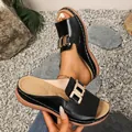 Close-up detail of black wedge slide sandals with gold buckle and thick sole - 36 / Black