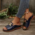 Mules à talon compensé bleu marine avec boucle dorée et bout ouvert portées par modèle - Bleu foncé