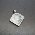 Close-up of diamond-shaped white crystal perfume bottle pendant with metal cap. - White Crystal / Silver