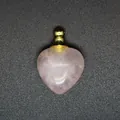 Dettaglio ravvicinato di un ciondolo diffusore di oli essenziali in quarzo rosa a cuore. - Quarzo rosa / Oro