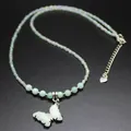 Macro detail view of a butterfly pendant necklace featuring mint green and iridescent beads - Amazonite