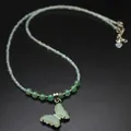 Macro detail of a green natural stone butterfly pendant on an elegant beaded necklace - Aventurine Jade