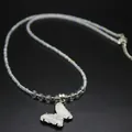 Detailed macro view of a white crystal butterfly pendant necklace with iridescent beads. - White Crystal