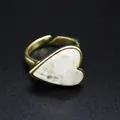 Close-up of a heart-shaped natural stone ring with a gold band on a dark background - White Crystal