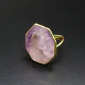 Gros plan d'une bague en pierre naturelle octogonale avec un anneau doré poli. - Améthyste