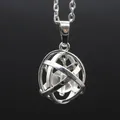 Macro detail of a silver-toned hollow sphere pendant with a clear gemstone bead inside - White Crystal