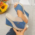 Close-up detail of blue denim wedge platform sandals with straw woven texture and metal logo. - Denim Blue