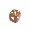 Primer plano de un dado de piedra de sol marrón brillante con puntos blancos. - Piedra de Arena Dorada
