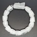 Detailansicht eines handgeschnitzten weißen Quarz-Drachenarmbands mit Drachenkopf - Weiß Kristall