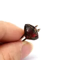 Detailed view of a vintage copper ring with a raw deep red gemstone inlay. - Garnet