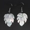 Close-up view of white monstera leaf earrings made of natural mother of pearl shell - Iridescent White Mother of Pearl (2)