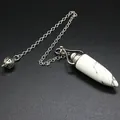 Close-up of white marble stone crystal pendulum with silver chain on black background - Howlite