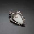 Detailed macro view of a vintage bronze heart pendant with translucent white stone. - White Crystal