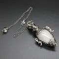Macro view of antique silver filigree pendulum with egg-shaped white moonstone - Pendant With Pendulum Chain / White Crystal