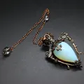 Close-up of a vintage medieval style moonstone pendant with an ornate bronze frame - Opal + Pendulum Chain