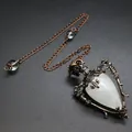 Close-up of vintage bronze pendulum necklace with white teardrop natural stone detail. - Clear Quartz + Pendulum Chain
