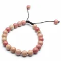 Detailed view of 8mm natural pink stone beads on a brown braided adjustable bracelet. - Red Wood Grain Stone