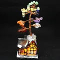 Close-up of handmade 7-chakra crystal money tree on glowing snow-covered house base - Snowy Cabin