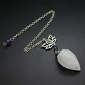 Detalle de un péndulo de cristal facetado con un colgante de loto y una cadena. - Cristal de roca