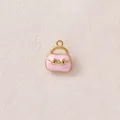 Nahaufnahme eines rosa Emaille-Taschenanhängers mit vergoldeter Schleife für DIY-Schmuck. - Rosa Tasche Stil