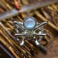 Macro detail of a silver spider-shaped open ring featuring a luminous natural moonstone. - Open Ring / Labradorite