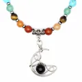 Primo piano del ciondolo a luna avvolto nel filo con pietra nera su collana di chakra. - Ossidiana